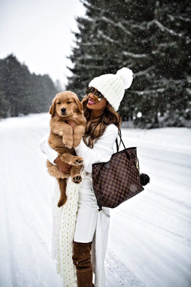 fashion blogger mia mia mine wearing a louis vuitton neverfull mm bag and white knit beanie with golden retriever puppy