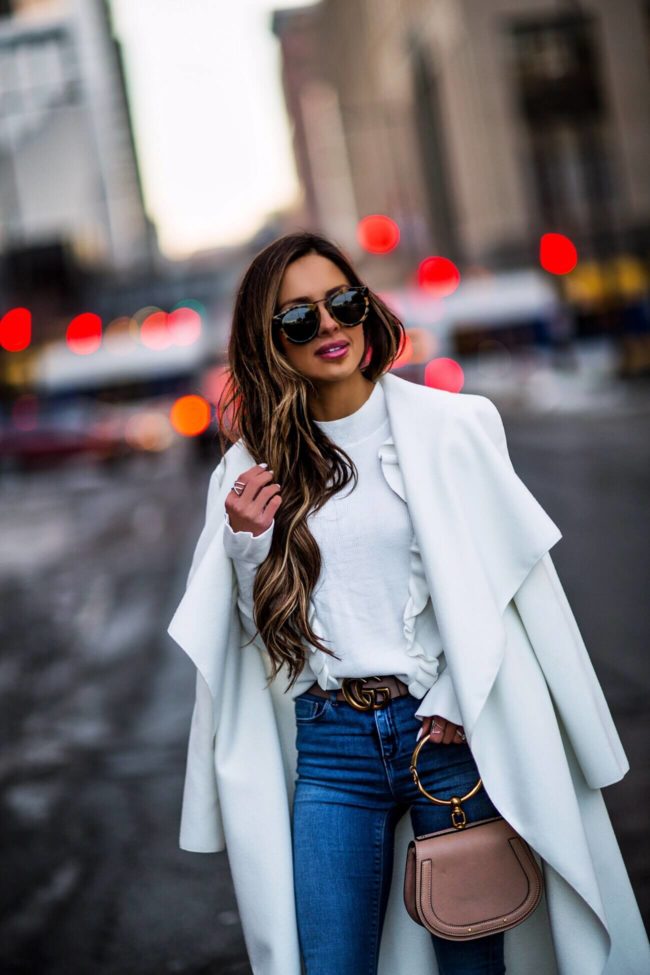 mia mia mine wearing a white coat and white ruffle top 