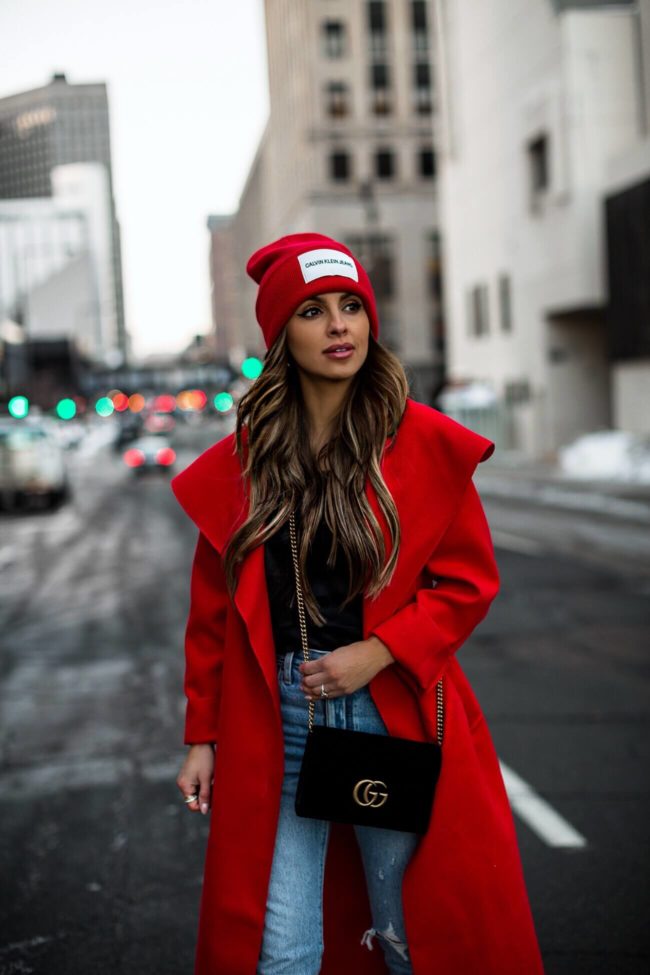 fashion blogger mia mia mine wearing a red calvin klein beanie and a red duster coat
