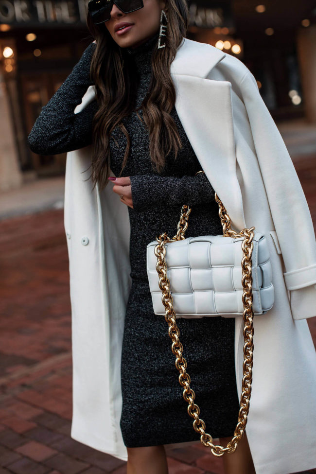 fashion blogger wearing a white coat and black dress from express