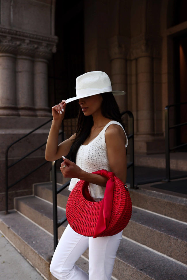 fashion blogger mia mia mine wearing a red straw bag from walmart and a white crochet top