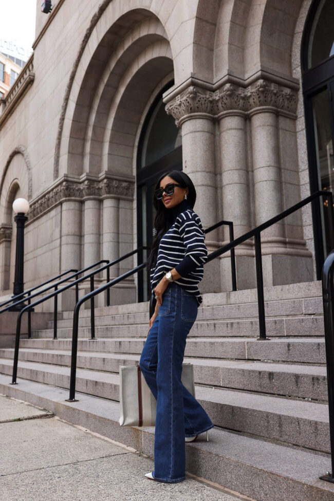 fashion blogger wearing a striped sweater and bootcut denim 