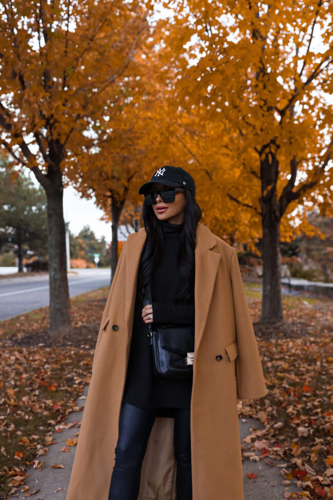 fashion blogger mia mia mine wearing a camel coat and black crossbody bag