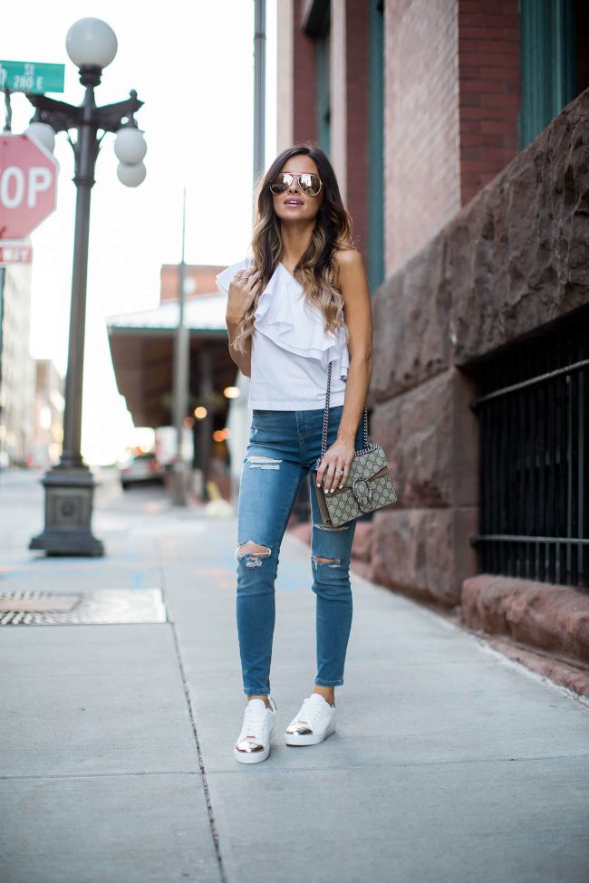 fashion blogger mia mia mine wearing a one shoulder top and ripped skinny jeans