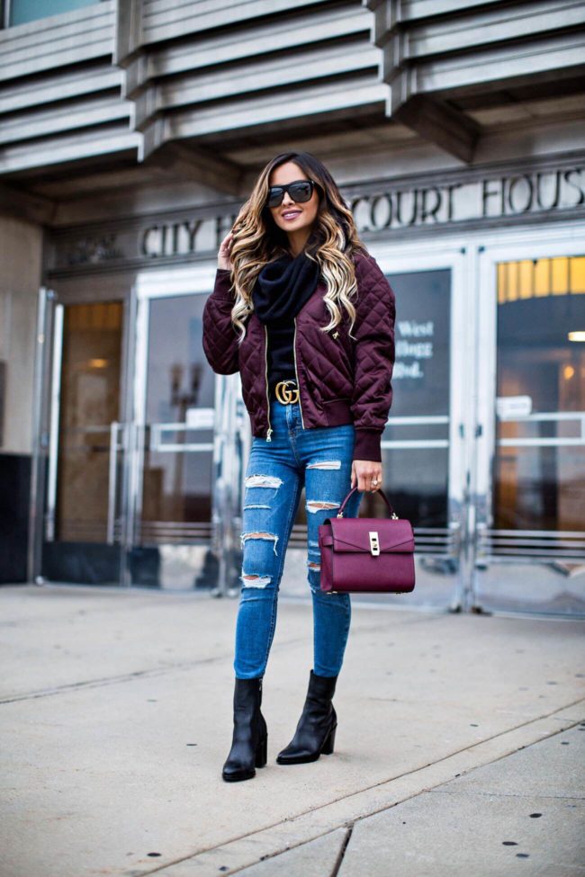 fashion blogger mia mia mine wearing an express burgundy silk bomber jacket and a burgundy mini bag from henri bendel