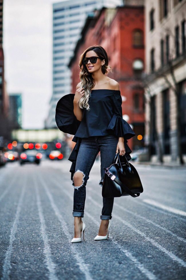 fashion blogger mia mia mine wearing a black bell sleeve off-the-shoulder top and white louboutin heels