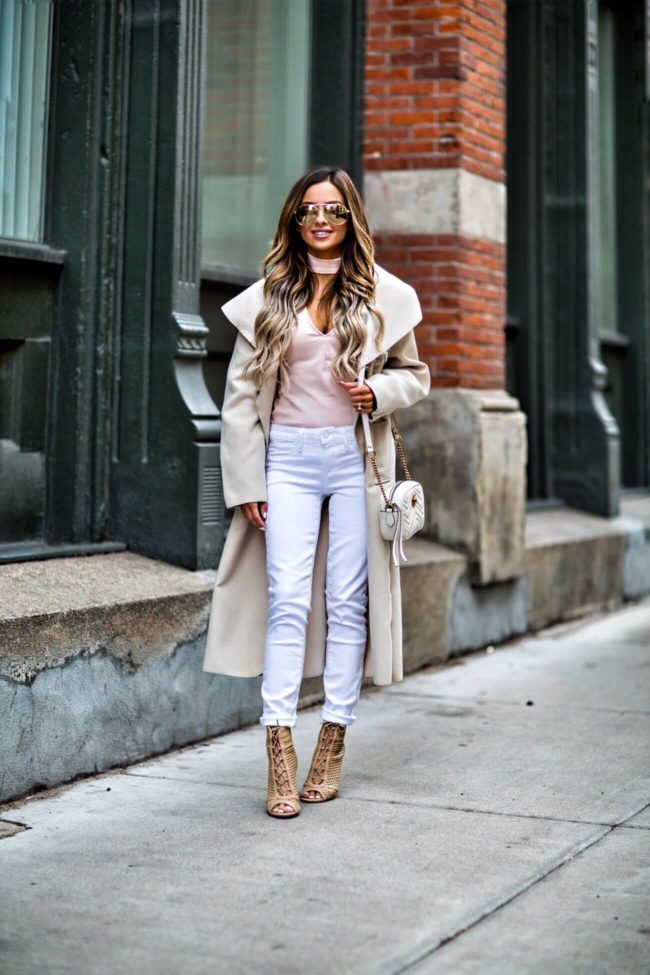 fashion blogger mia mia mine wearing a pink cutout top from bebe and white paige jeans