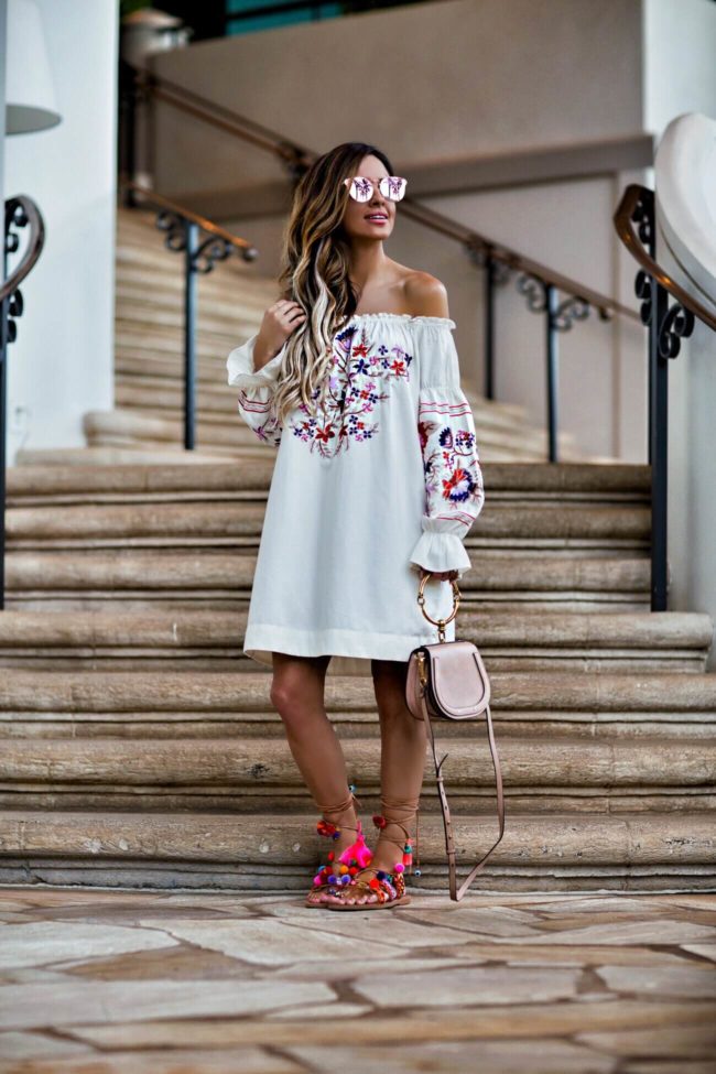 fashion blogger mia mia mine wearing an embroidered dress by free people from shopbop and pom pom sandals