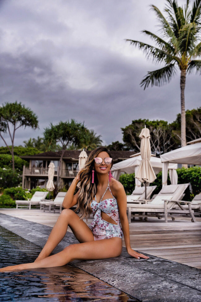 fashion blogger mia mia mine wearing a pink floral swimsuit at the four seasons resort hualalai in hawaii
