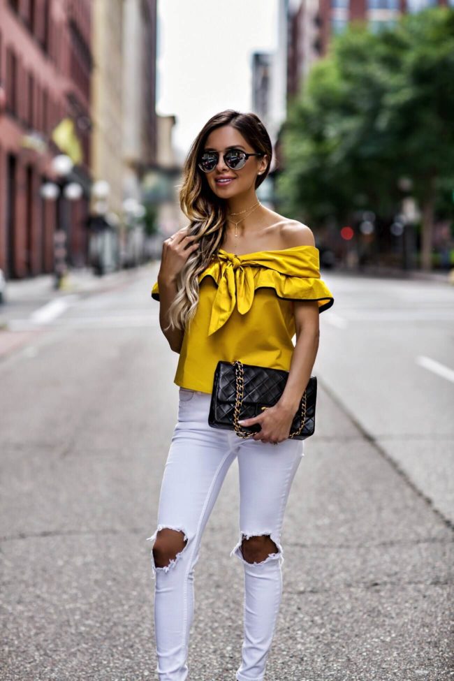 fashion blogger mia mia mine wearing a mustard off-the-shoulder top and a chanel 2.55 bag