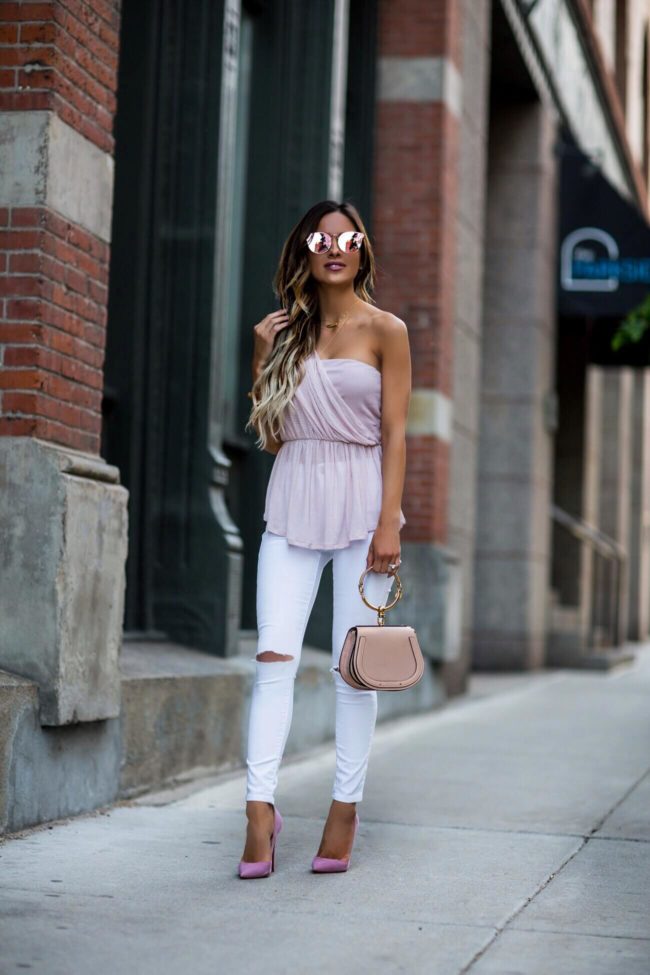 fashion blogger mia mia mine wearing a pink one-shoulder top from free people and white denim 