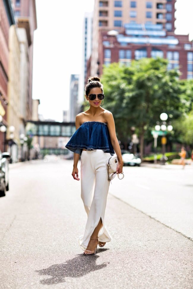fashion blogger mia mia mine wearing a denim strapless top and white pants from revolve