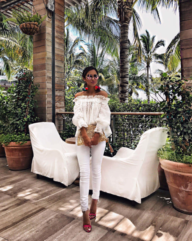 fashion blogger mia mia mine wearing a white off-the-shoulder top and pom pom earrings from tuckernuck