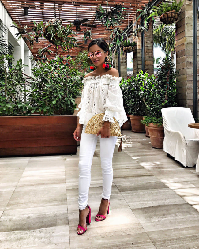 fashion blogger mia mia mine wearing a white off-the-shoulder top and pom pom earrings in Miami