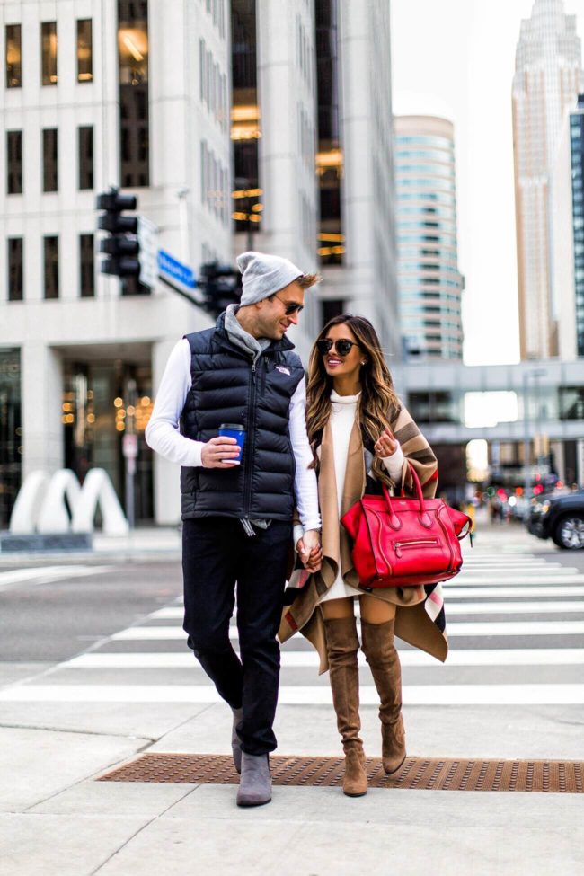 fashion blogger mia mia mine wearing a red celine bag and a burberry cape with husband in a north face vest