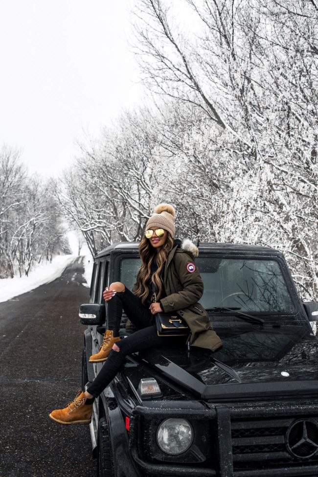 fashion blogger mia mia mine wearing a canada goose parka sitting on a mercedes g wagon