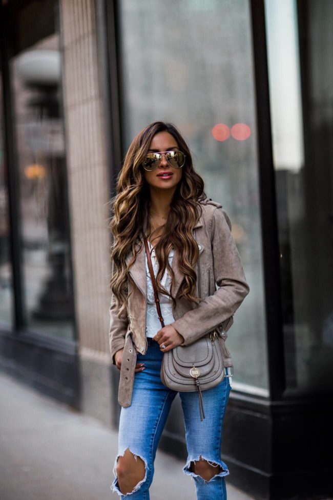 fashion blogger mia mia mine wearing a suede moto jacket and a see by chloe crossbody bag from bloomingdale's