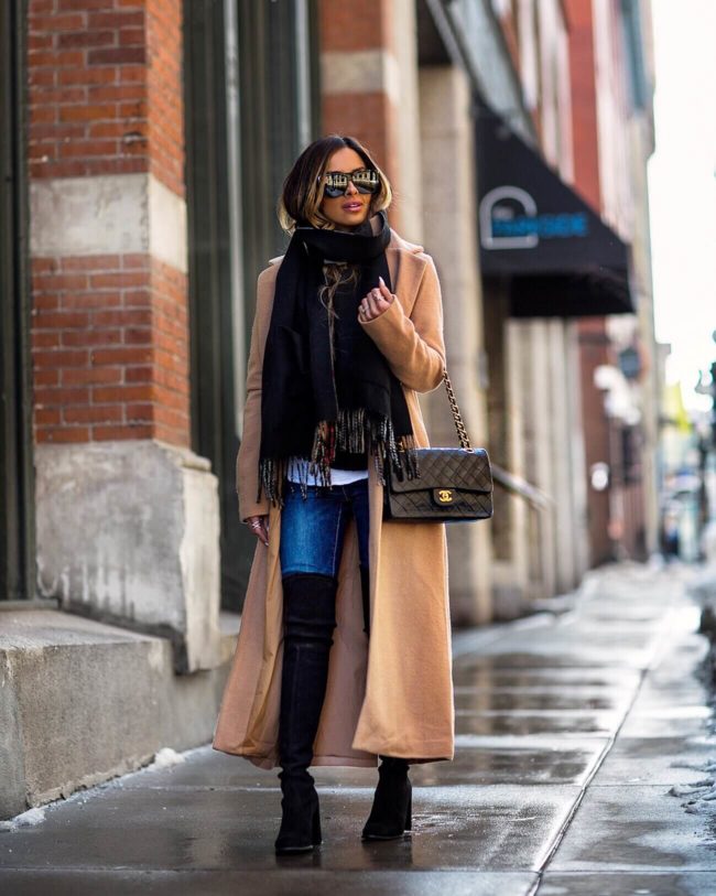 mia mia mine wearing a camel coat from revolve and black over-the-knee boots