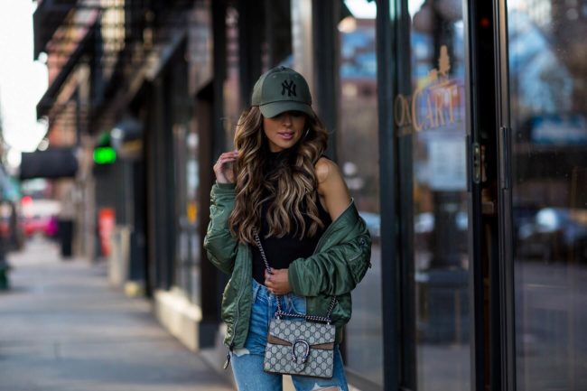 fashion blogger mia mia mine wearing an ny baseball hat and a bomber jacket from revolve