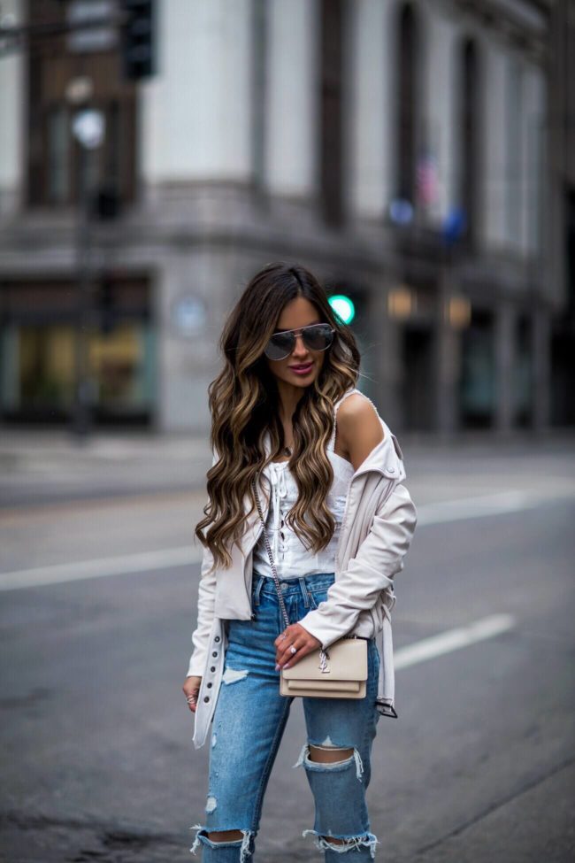 fashion blogger mia mia mine wearing a saint laurent sunset crossbody bag and a cupcakes and cashmere suede moto jacket