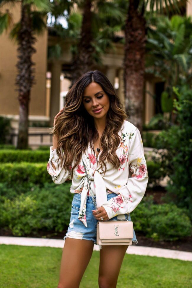 fashion blogger mia mia mine wearing a floral bodysuit from revolve and lovers + friends denim shorts