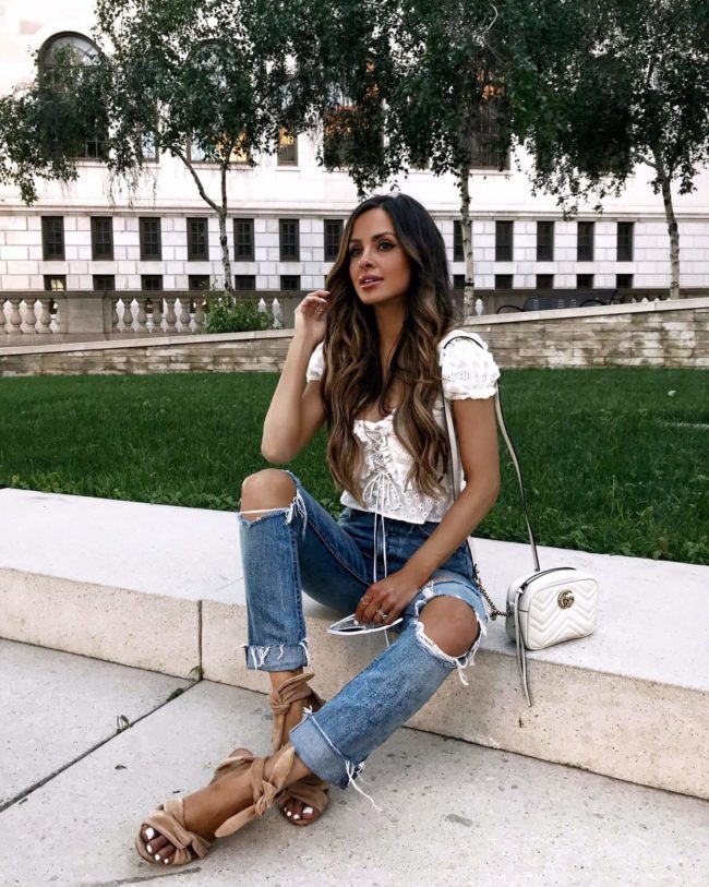 fashion blogger mia mia mine wearing a white eyelet top and denim jeans from revolve
