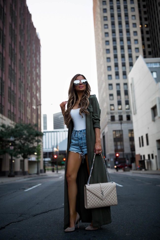 fashion blogger mia mia mine wearing an olive trench coat from revolve and a saint laurent envelope bag
