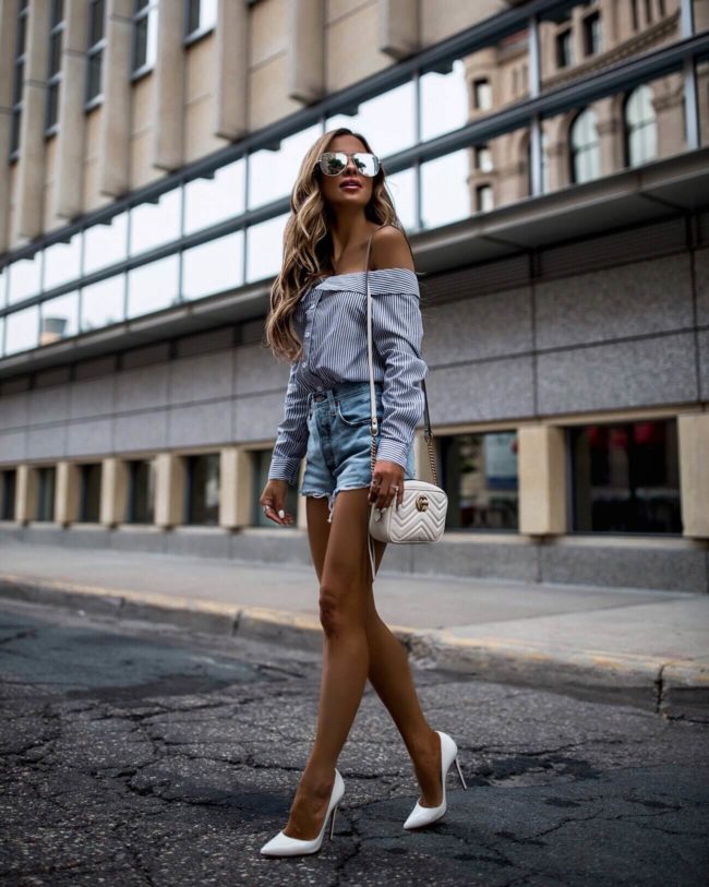 fashion blogger mia mia mine wearing a blue and white striped top and levi's denim shorts