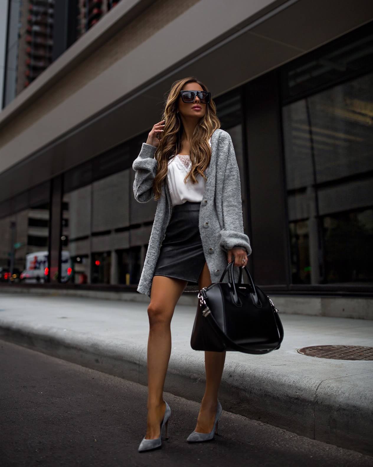 fashion blogger mia mia mine wearing a grey cardigan and a faux leather skirt from revolve
