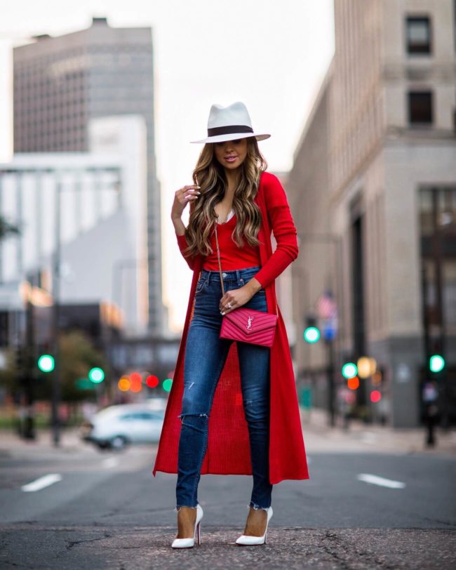 fashion blogger mia mia mine wearing a red duster sweater from revolve and a white panama hat by rag & bone