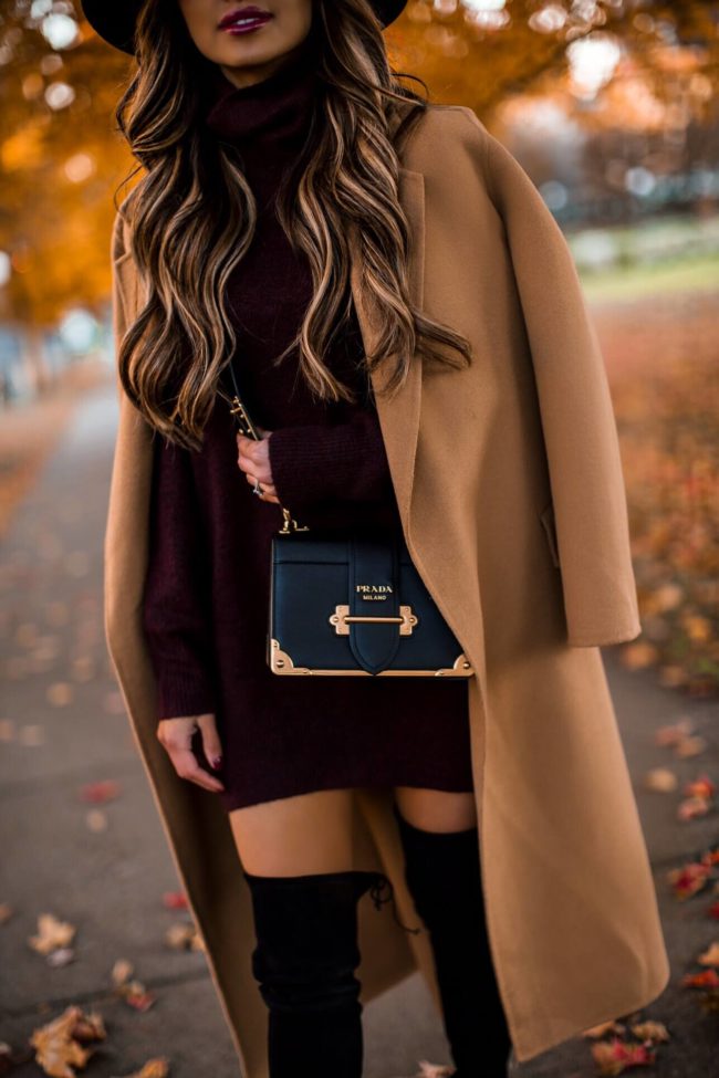 fashion blogger mia mia mine wearing a burgundy sweater dress and a camel coat