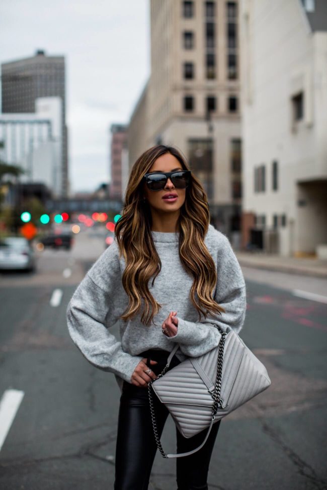 fashion blogger mia mia mine wearing a grey crew sweater and faux leather blank denim pants