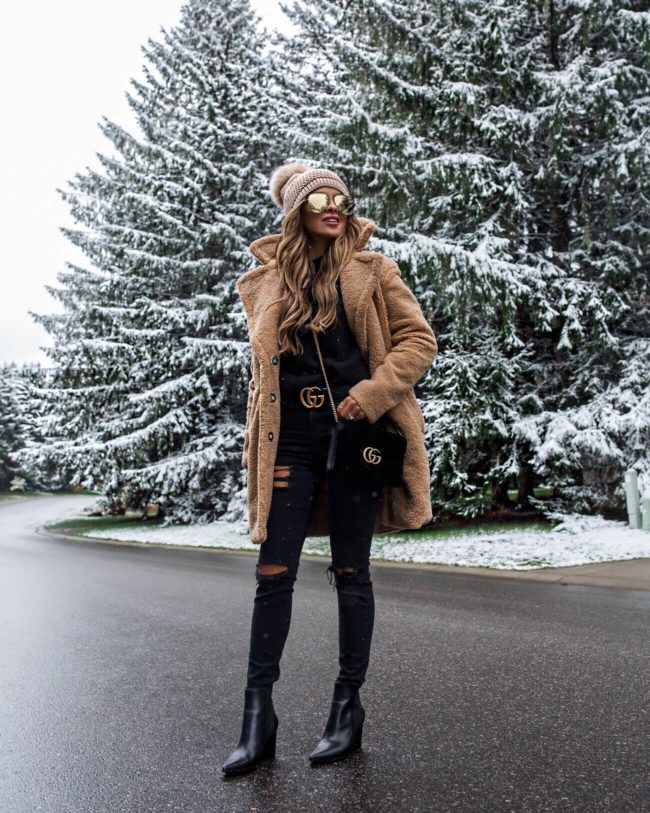 fashion blogger mia mia mine wearing a pom pom beanie hat and a gucci belt in the snow