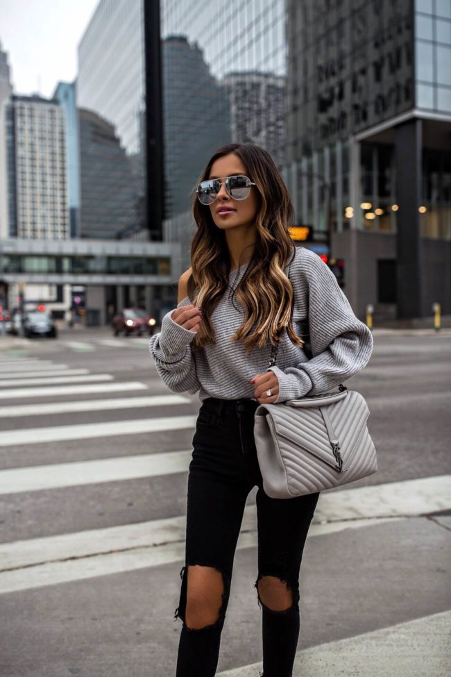 fashion blogger mia mia mine wearing a gray off-the-shoulder sweater from intermix and a gray saint laurent large college bag