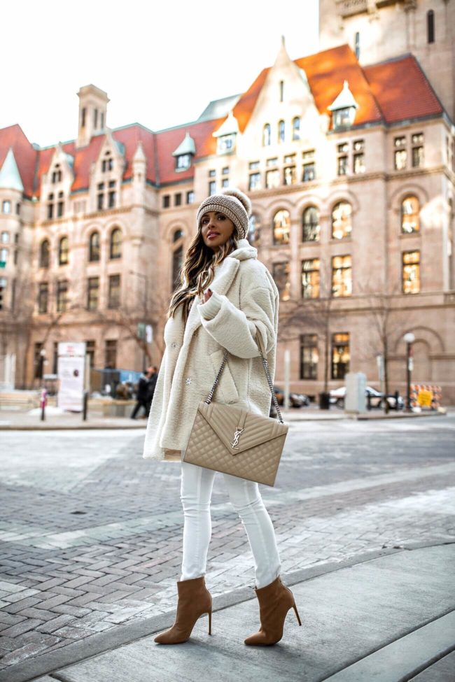 fashion blogger mia mia mine wearing an all white winter outfit with a saint laurent envelope bag