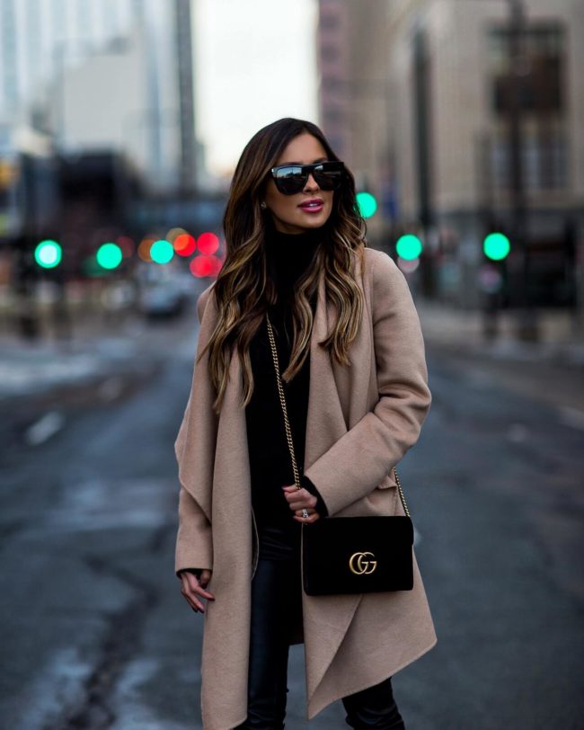 fashion blogger mia mia mine wearing a camel coat and all black outfit for winter