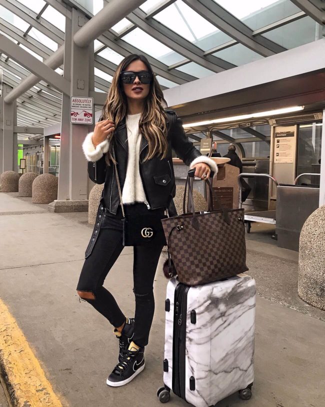 fashion blogger mia mia mine wearing a gucci velvet bag and a fuzzy sweater from revolve at the airport