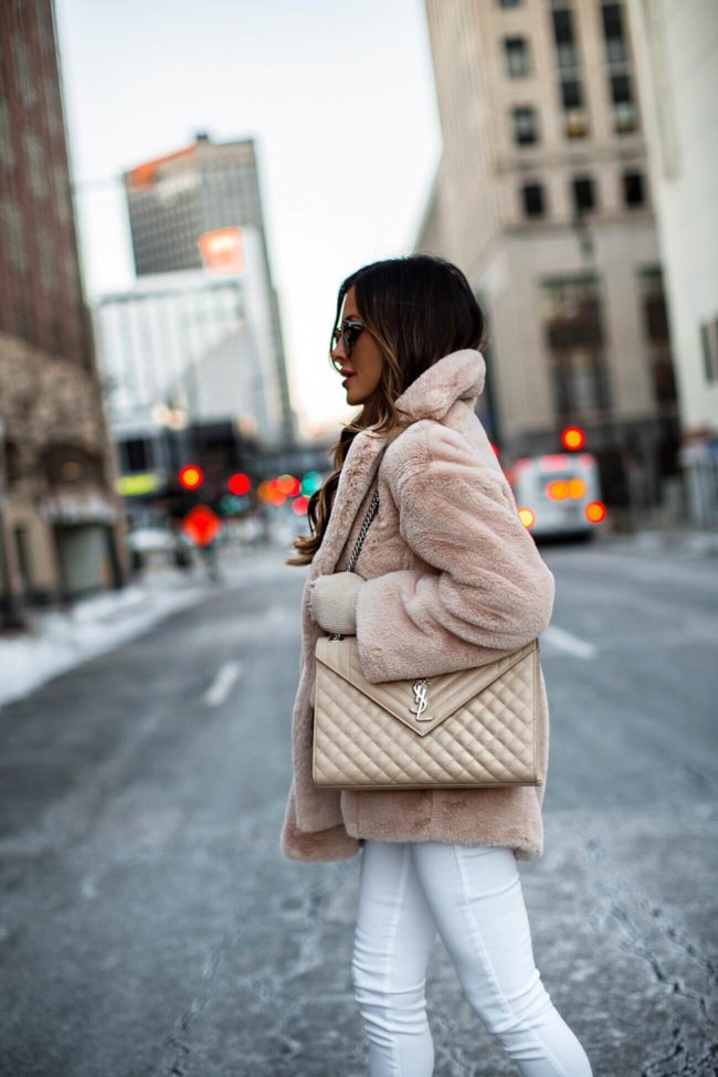 fashion blogger mia mia mine wearing a large saint laurent envelope bag with a faux fur teddy bear coat