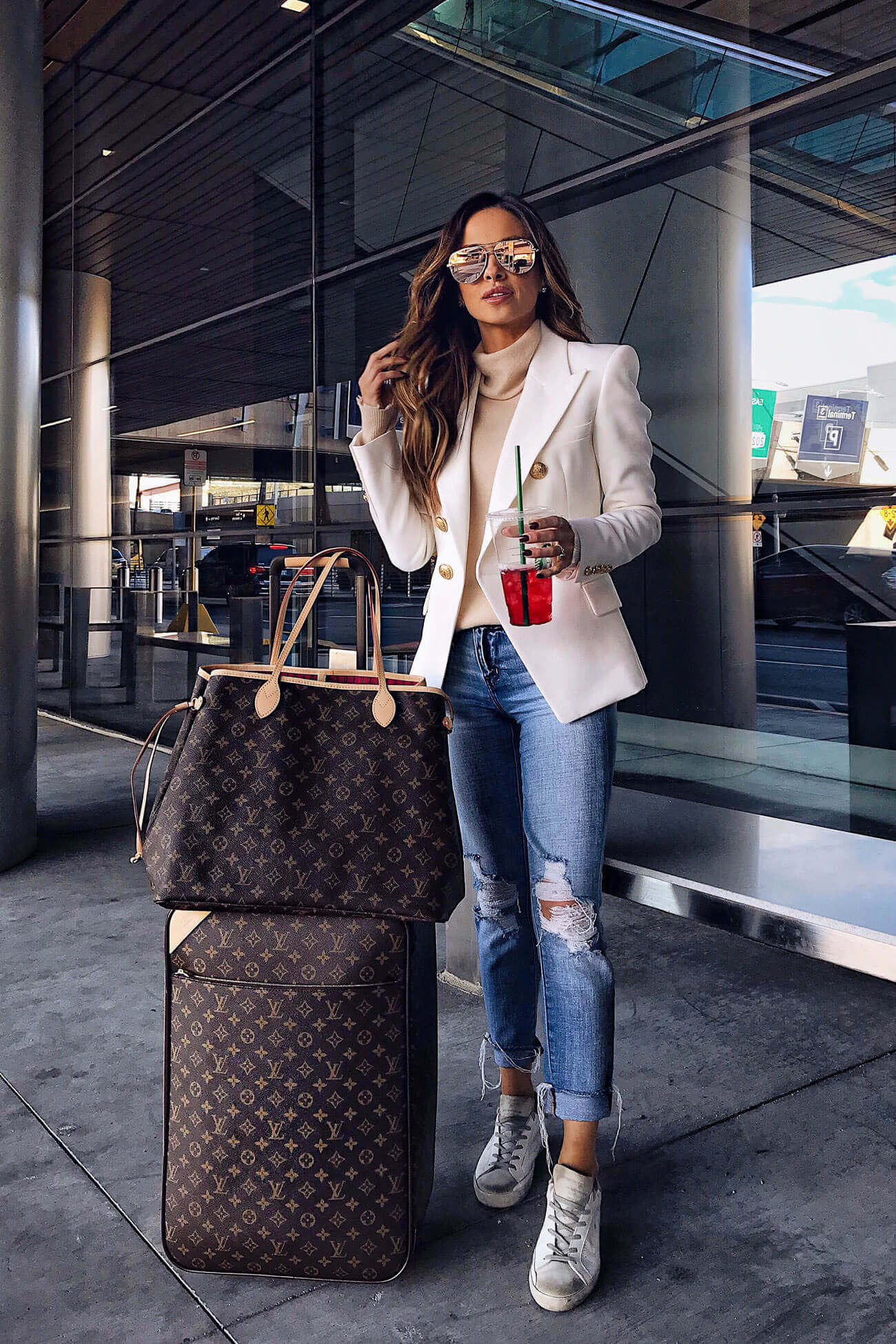 fashion blogger mia mia mine traveling with a louis vuitton pegase suitcase and a louis vuitton neverfull gm