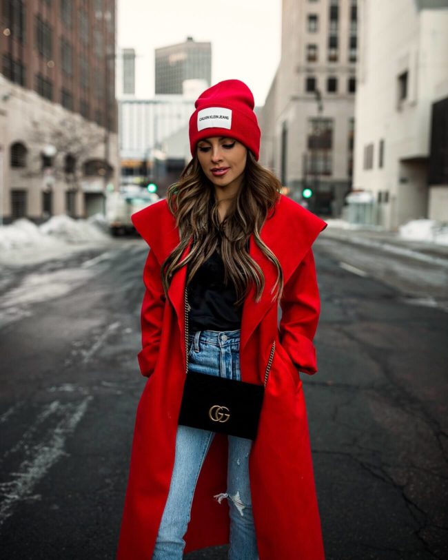 fashion blogger mia mia mine wearing a red duster coat and a calvin klein beanie