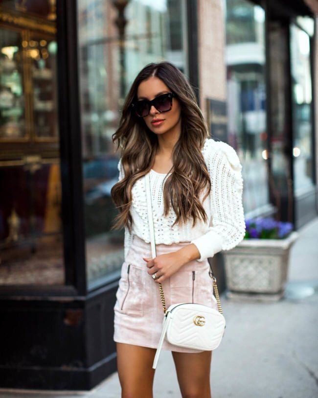 fashion blogger mia mia mine wearing a white bcbg crochet sweater and a pink faux suede skirt