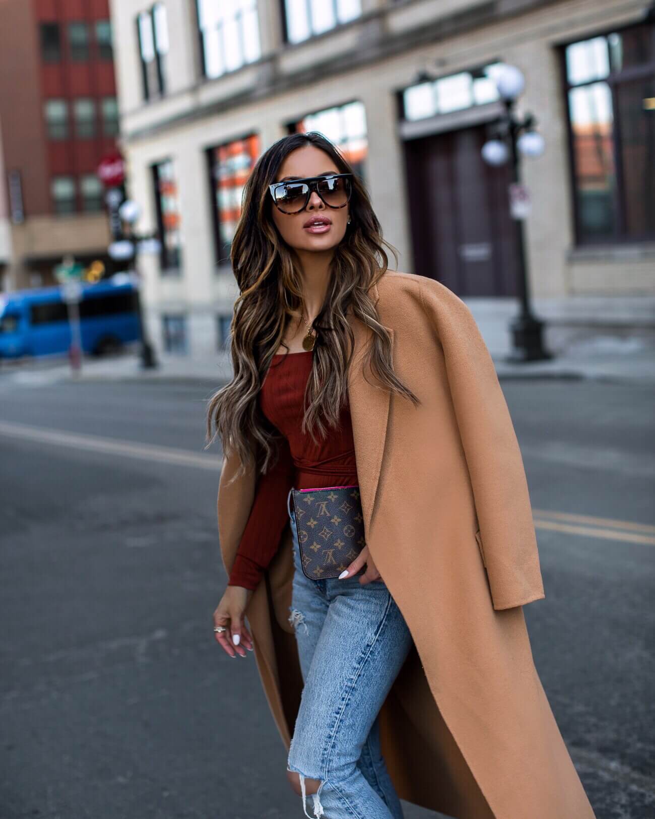 fashion blogger mia mia mine wearing a camel coat and louis vuitton clutch