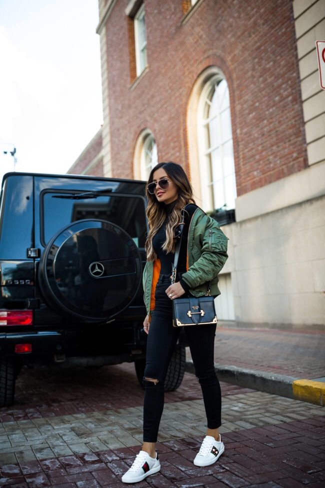 fashion blogger mia mia mine wearing an alpha industries bomber jacket and gucci sneakers
