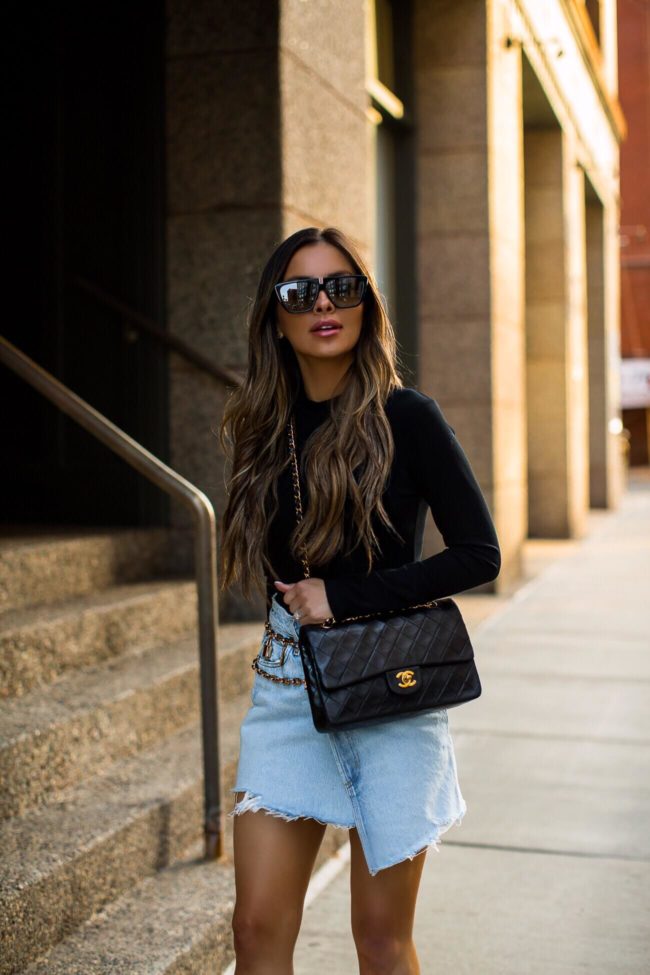 fashion blogger mia mia mine wearing a black bodysuit and agolde denim skirt
