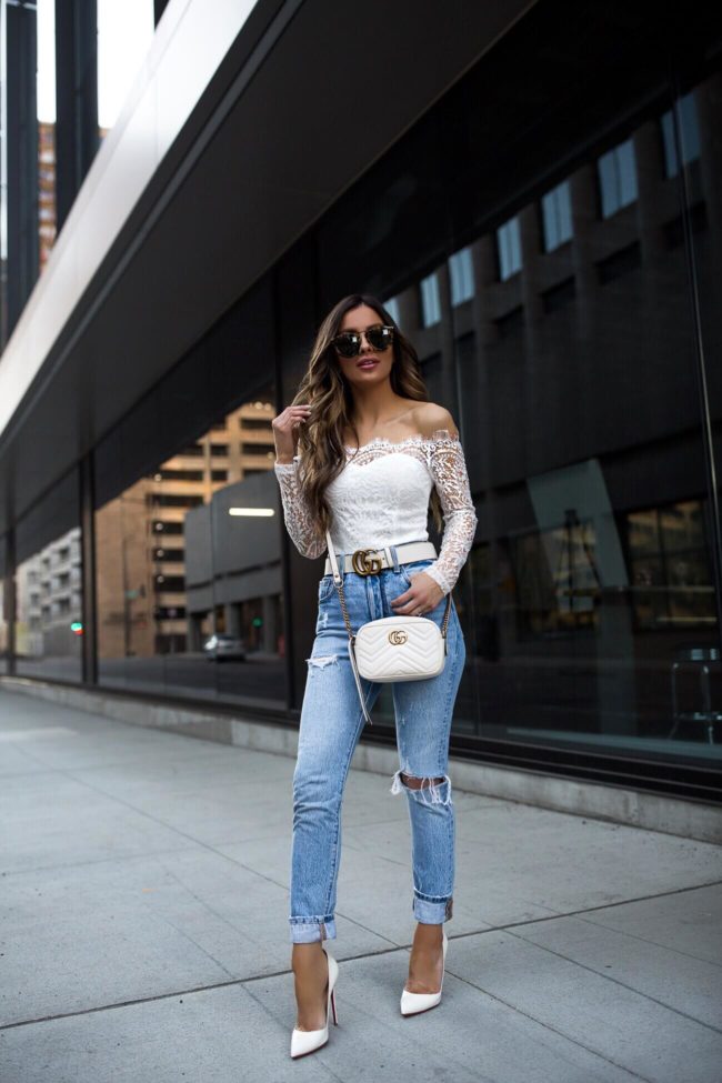 fashion blogger mia mia mine wearing a white long sleeve lace bodysuit and a white gucci bag with levi's jeans 