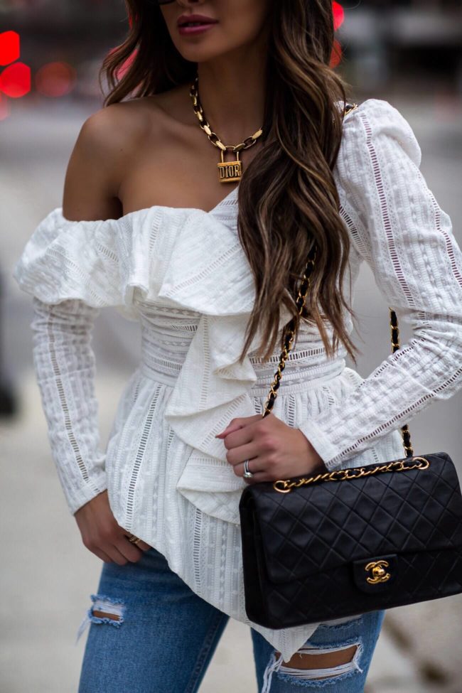 fashion blogger mia mia mine wearing a white lace off-the-shoulder top and a dior lucky locket necklace for spring 2019
