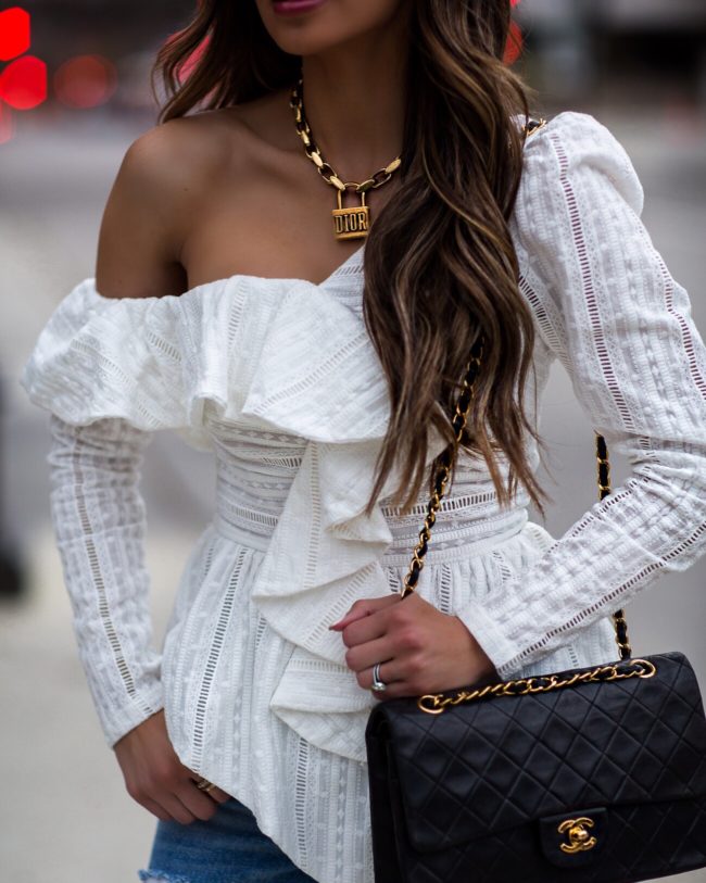 fashion blogger mia mia mine wearing a white lace top and a dior lucky locket necklace