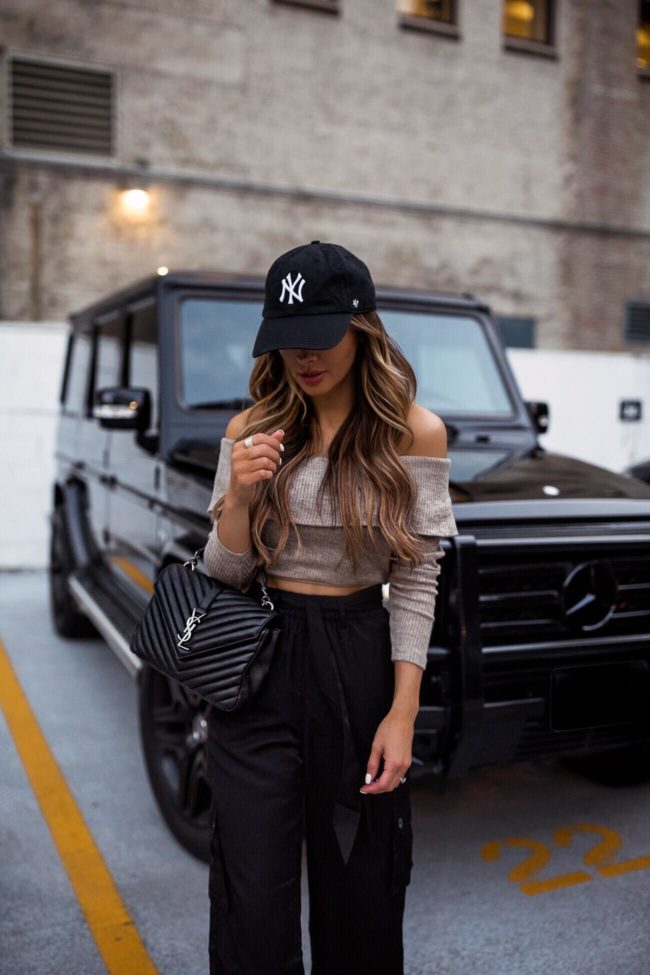fashion blogger mia mia mine wearing a revolve crop top with a new york yankees cap and a saint laurent college bag