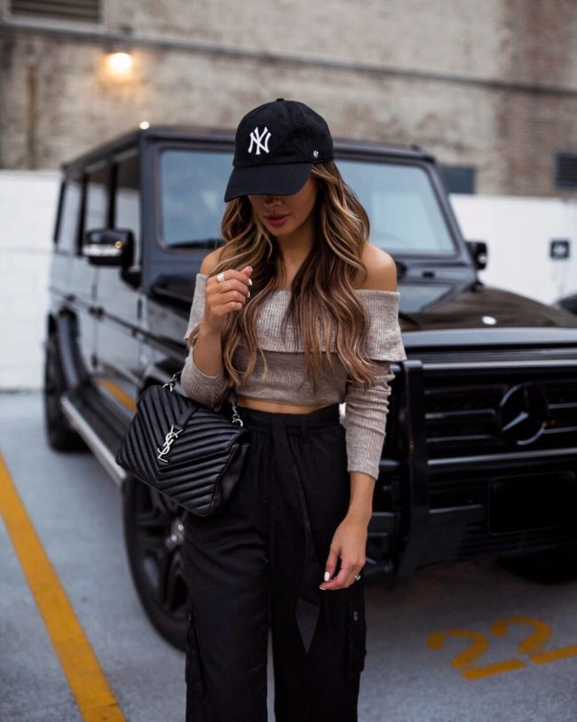fashion blogger mia mia mine wearing a revolve crop top with a new york yankees cap and a saint laurent college bag