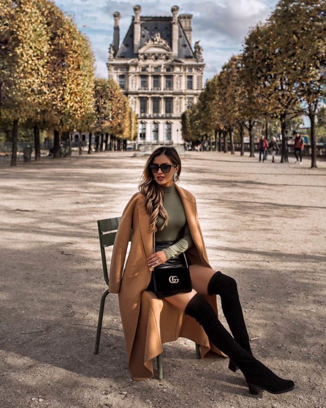 fashion blogger mia mia mine wearing a camel coat at the jardin des tuileries in paris